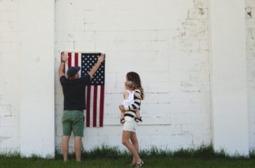 man-holding-u-s-us-flag-next-to-woman-and-child