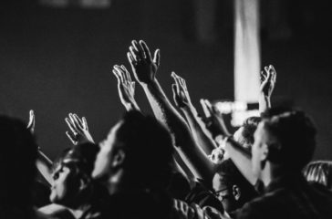 grayscale-photo-of-people-raising-their-hands-1666816/